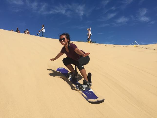 UTA Student sandboarding down large sand dune