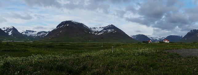 Landscape photo of mountains behind a green field