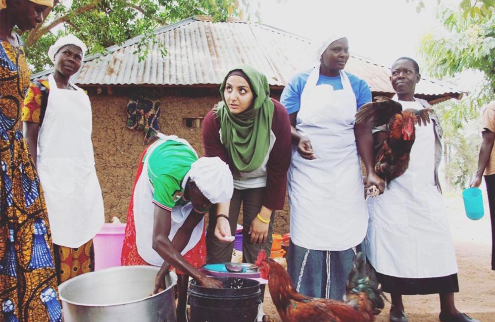 A UTA student is cooking with women in a village in Tanzania.